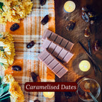 Brown wax melt bars with caramelised dates on a wooden surface with candles and flowers.