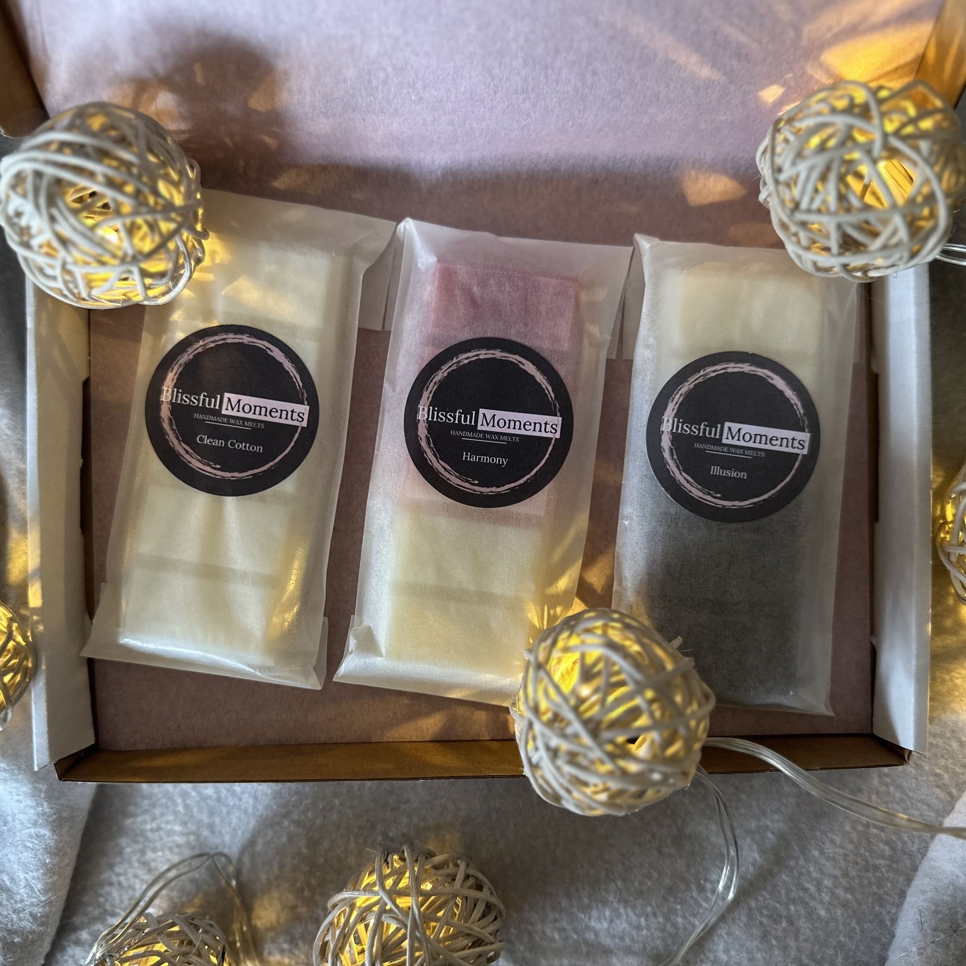 White, red and black soy wax melts sitting in a nicely presented gift box surrounded by fairy lights