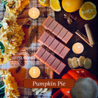 Pumpkin pie snapbar wax melts surrounded by candles, cinnamon sticks and flowers on a checkered cloth.