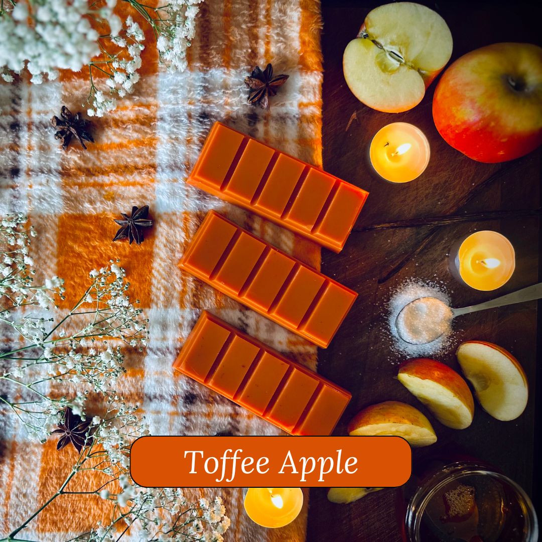 Toffee Apple snapbar wax melts surrounded by apples, and candles on a checkered fabric background.
